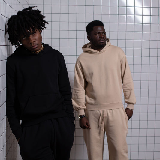 Two people wearing black and beige pullover hoodies