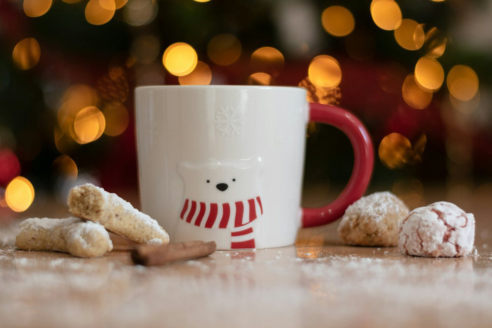 White holiday mug with a red handle next to Christmas cookies