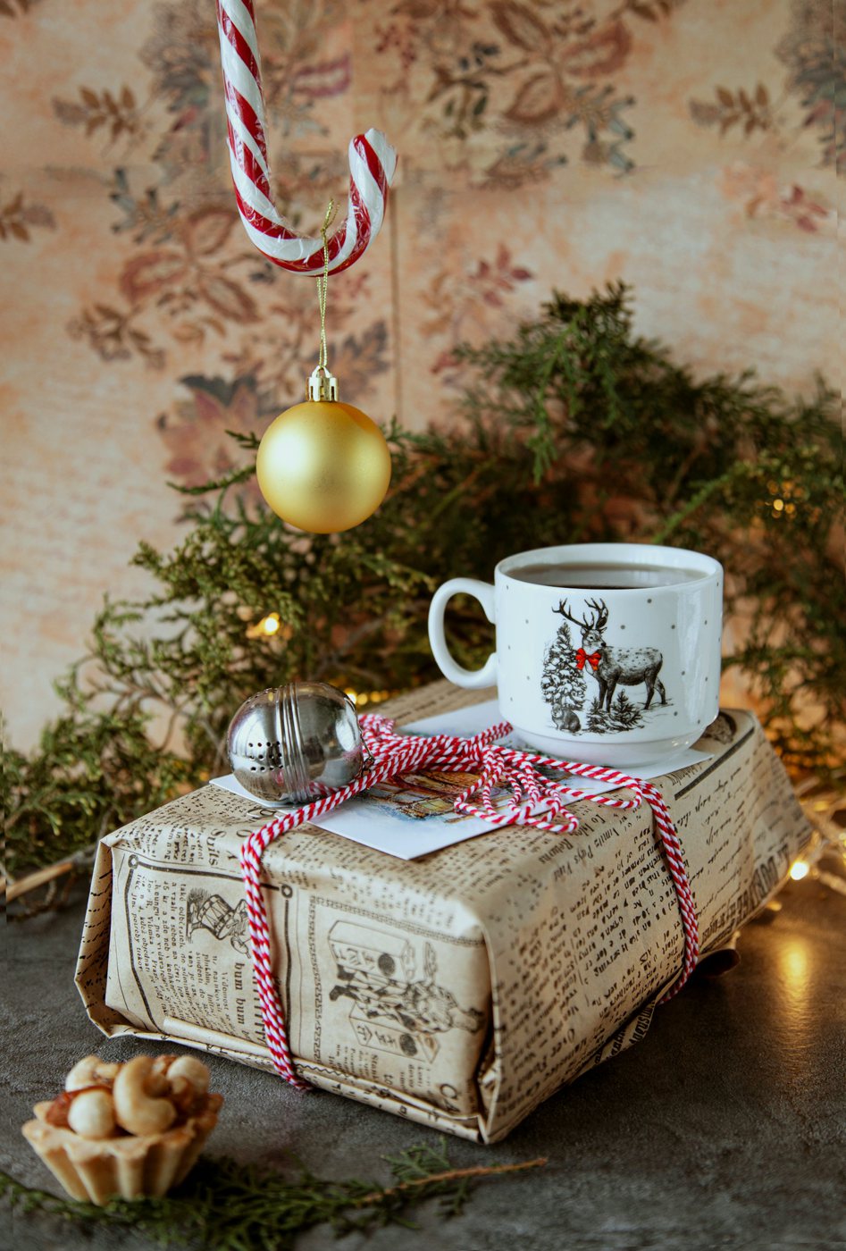 Wrapped gift with a reindeer mug and a gold Christmas ornament